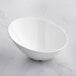 An Acopa white melamine bowl on a marble surface.