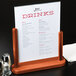 An American Metalcraft mahogany table top board with a menu on a stand holding a glass of drinks.