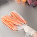 A hand in a plastic bag of carrots.