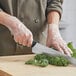 A person cutting kale with Choice disposable CPE gloves.
