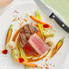 A plate with a Rastelli's Filet Mignon and vegetables with a knife and fork.