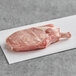 A Rastelli's bone-in pork steak on a white surface.