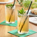 Two glasses of Tractor Beverage Co. green tea with straws and mint leaves on a table.