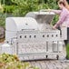 A woman cooking food on a Backyard Pro stainless steel outdoor grill.