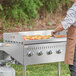 A man using a Backyard Pro griddle plate to cook food on a grill.