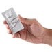 A hand holding a small white sachet of Dial White Marble Breck Conditioning Shampoo.