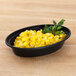 A Pactiv Newspring VERSAtainer oval microwavable container filled with corn on a table with parsley.