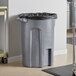 A Toter dark gray granite trash can with a black bag inside.