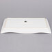 A white rectangular stoneware platter with a wavy border and a logo on it.