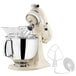 A white KitchenAid Artisan stand mixer with an attachment.