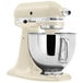 A cream colored KitchenAid Artisan stand mixer with a bowl attached.
