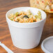 A white Dart foam food container filled with pasta and vegetables.
