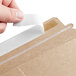 A person using a piece of tape to close a brown Lavex Stayflats mailer.