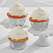 Three Enjay silver foil baking cups with cupcakes with white frosting.