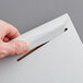 A person's hand opening a Lavex Stayflats white rigid mailer with a paper clip.