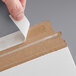 A person using tape to seal a piece of paper inside a Lavex Stayflats mailer.