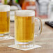 Two Acopa Paneled Beer Mugs filled with beer on a table.