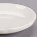 A CAC ivory scalloped edge saucer on a gray surface.