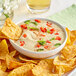A bowl of food with tortilla chips in a bowl of dip.