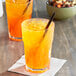 Two plastic cups of Jones Orange & Cream soda with straws.