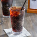 A glass of Jones Cola soda with ice and a straw.