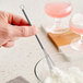 A hand using a Choice stainless steel mini whisk to mix white ingredients in a bowl.