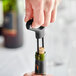 A hand using the black Franmara Jubilee two-prong cork extractor to open a bottle of wine.