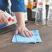 A person spraying a Dixie Blue Stripe disposable foodservice towel on a table.