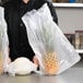 A person holding a plastic bag with pineapples in it.