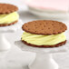 A close up of a cookie with yellow frosting on top and a vanilla ice cream sandwich.