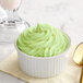A bowl of green Creamery Ave. pistachio soft serve mix on a counter with a spoon.
