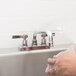 A person washing their hands in an Advance Tabco drop in stainless steel sink.