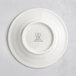 A white RAK Porcelain flat plate with an embossed crown logo.
