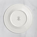 A white RAK Porcelain flat plate with an embossed crown logo.
