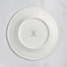 A white RAK Porcelain plate with an embossed crown logo on the rim.