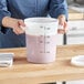 A woman holding a measuring cup with pink liquid.