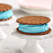 Two ice cream sandwiches with blue frosting on cookies.
