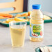 A bottle of Mott's Mighty Soarin' Apple Juice on a table next to a glass of apple juice.