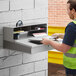 A man in a safety vest opening a box on a Lavex stainless steel wall mount receiving desk.