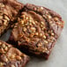 A close up of a brownie with roasted unsalted granulated peanuts on top.