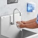 A person washing their hands with a Regency Wall Mount Handsink Faucet using the foot pedal valve.