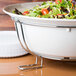 A chrome rack holding six bowls of salad on a table.