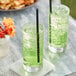 Two glasses of Pure Craft Cucumber Lime soda with straws on a marble surface.