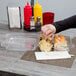 A person putting a sandwich in a Durable Packaging clear hinged plastic container.