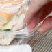 A hand holding a Durable Packaging clear hinged lid plastic container with food inside.