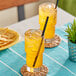 Two glasses of Jarritos Mandarin soda with straws on a table.