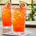 Two glasses of Pure Craft Beverages Strawberry Watermelon beverage with fruit slices and a slice of fruit on top.