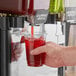 A hand holding a glass of red Pure Craft Beverages Raspberry Hibiscus Tea.