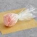 A Chalet Desserts strawberry shortcake cake pop in pink and white plastic wrap.