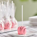 A Chalet Desserts chocolate strawberry cake pop on a white stick on a white plate.